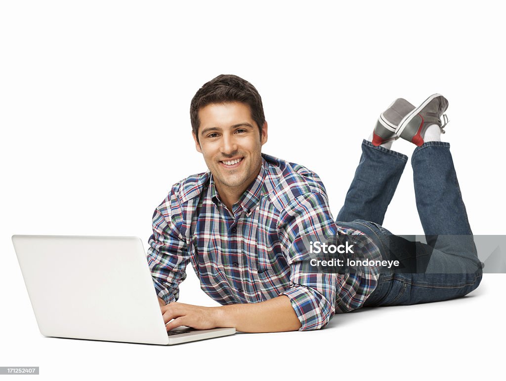 Zrelaksowany młody człowiek za pomocą laptopa-izolowano - Zbiór zdjęć royalty-free (Leżeć)