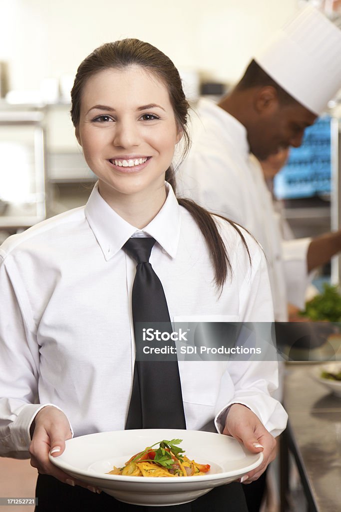 Jeune Serveuse tenir un plat préparé dans la cuisine de notre restaurant - Photo de Cravate libre de droits