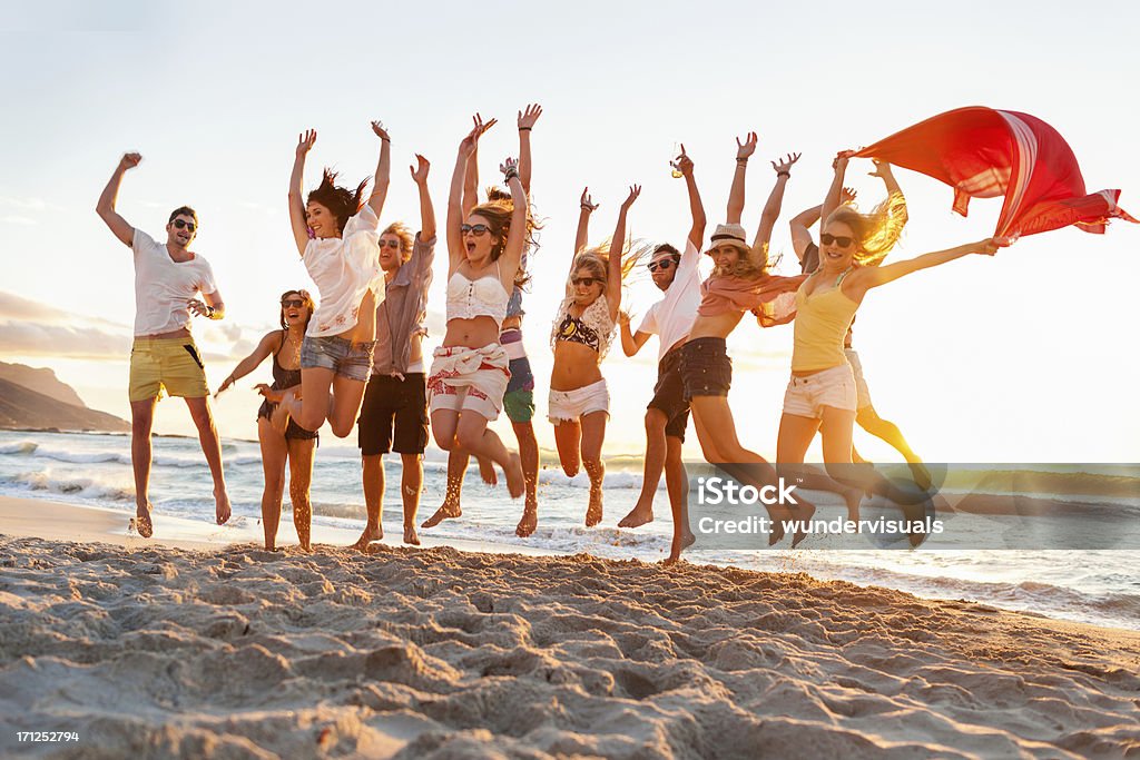 Jovens pulando em uníssono, na praia - Foto de stock de Praia royalty-free