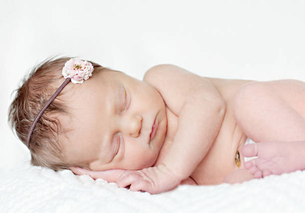 Sonno neonato bambino ragazza con fiore fascia per capelli - foto stock