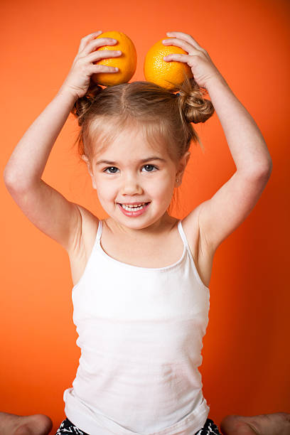 istock Cute Little Girl with Oranges on Orange Background 171253104
