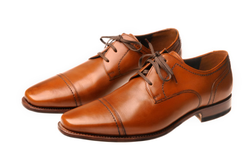 Pair of brown leather shoes isolated on a white background.