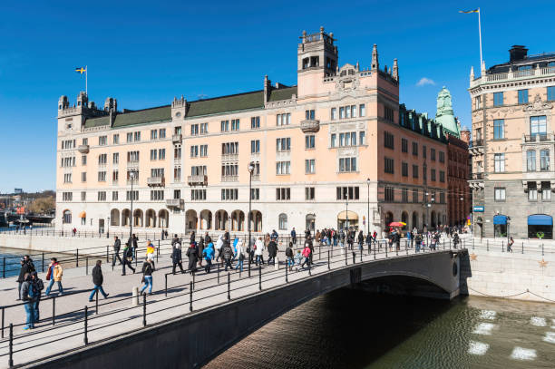 Stockholm crowds on Riksbron bridge beside Rosenbad "Stockholm, Sweden - April 7th, 2012: Locals and tourists strolling across Strommen on Riksbron, the National Bridge, in the spring sunshine towards the historic Rosenbad building that is home to the Swedish Prime Minister's office." strommen stock pictures, royalty-free photos & images