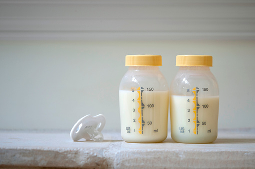 2 bottles of pumped breast milk with a pacifier
