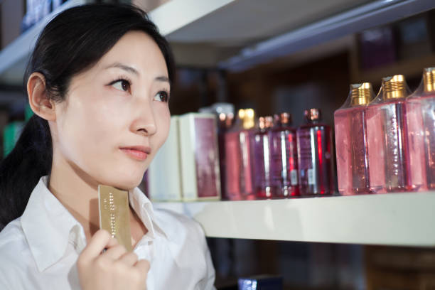 Bottle perfume female hand. Young woman holding bottle of perfume. Fashionable perfumes in hands of women. Girl sprays perfume. Beautiful women's hands.