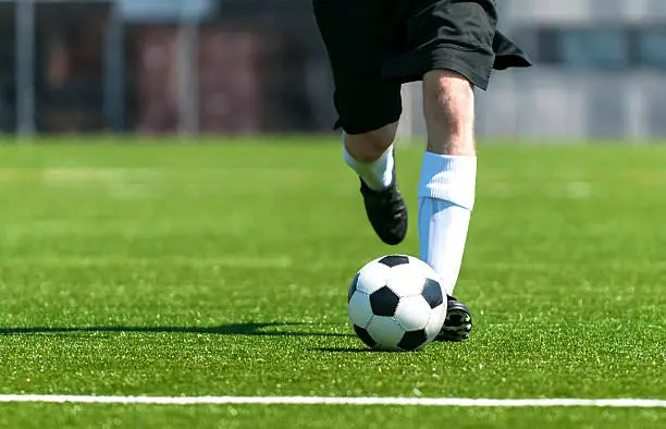 Soccer player runs and kicks the ball on a beautiful soccer field.