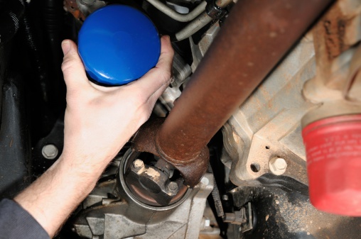Close up of hand grabbing oil filter under car or truck to change oil.