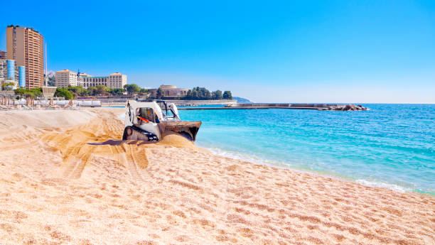 Small digger leveling sand on beach stock photo