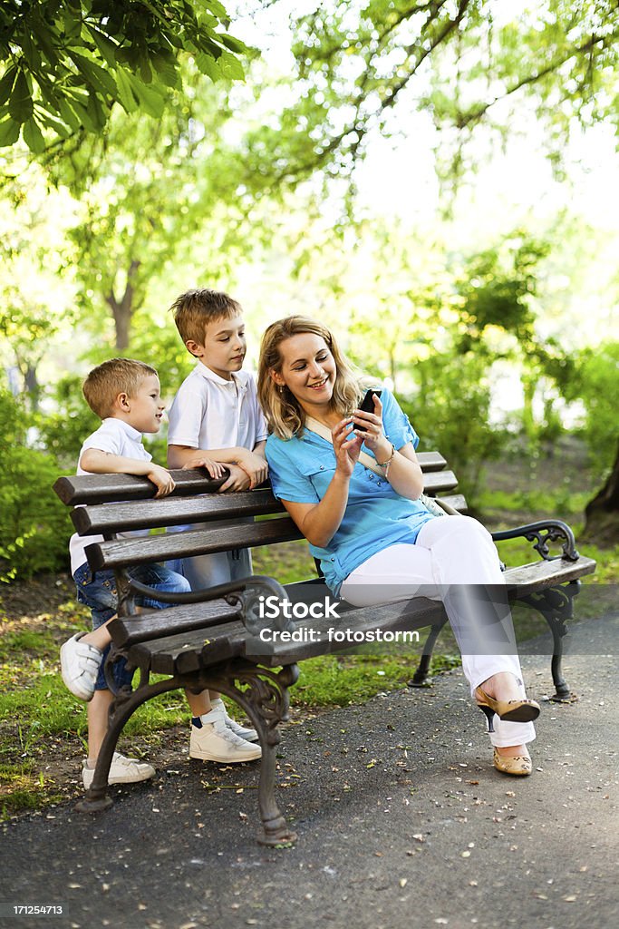 Mère et enfants à l'aide d'un téléphone mobile dans le parc - Photo de Famille libre de droits