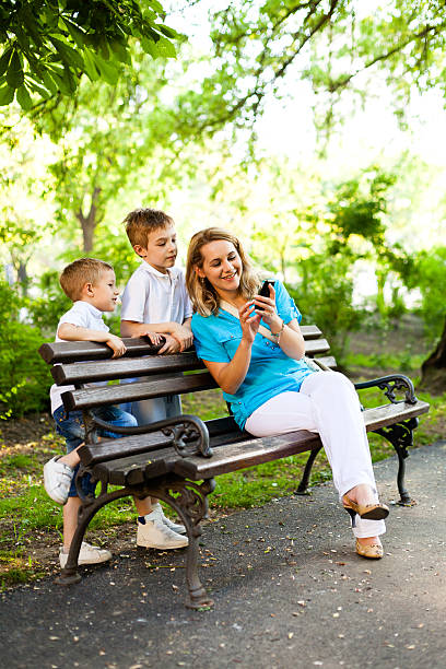 istock Mother and children using mobile phone in the park 171254713