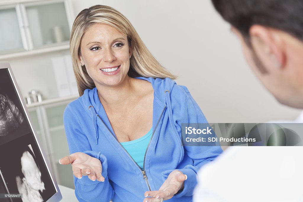 Pregnant woman asking doctor a question about her sonogram Pregnant woman asking her doctor a question about her sonogram.  Adult Stock Photo