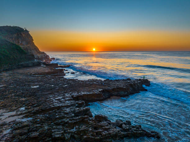 istock Sunrise over the ocean and rock platform with clear skies 1712573613