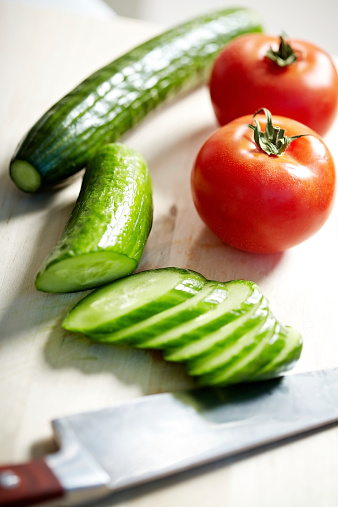 Close-up of tomatoes and sliced cucumber on kitchen table