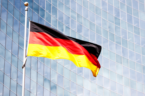 The German flag, Bundesflagge, flying against the backdrop of a modern glass office building