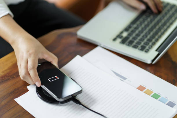 istock Charging mobile phone battery with wireless charging device in the table. Smartphone charging on a charging pad. Mobile phone near wireless charger Modern lifestyle technology concept 1712606049