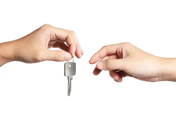 "Close-up on a hand giving a key to another, isolated on white background. Clipping path included."