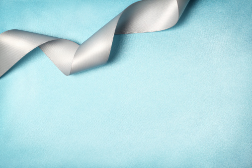 Curly white ribbon on blue silk texture background.