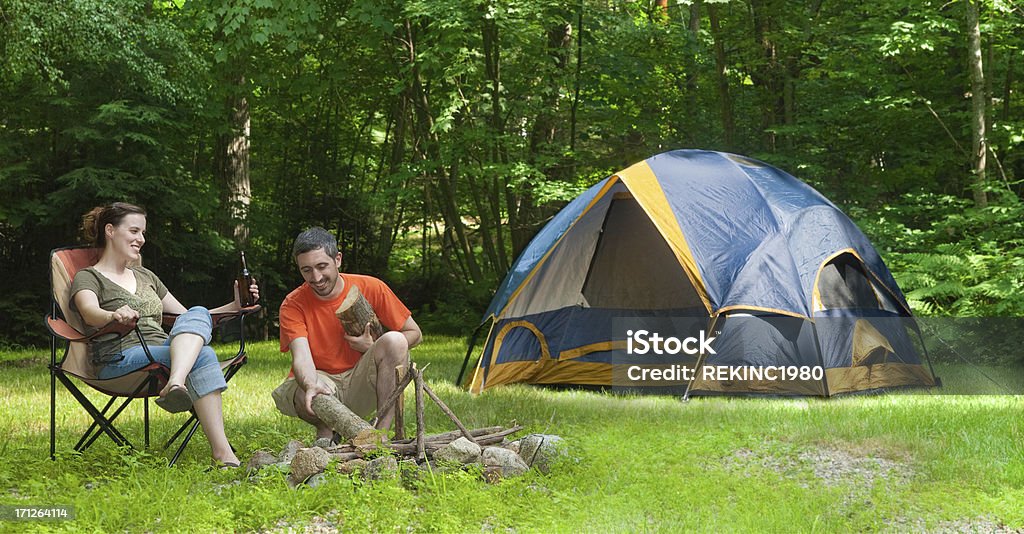Uomo e donna in campeggio tenda a un fuoco di accampamento - Foto stock royalty-free di Amicizia