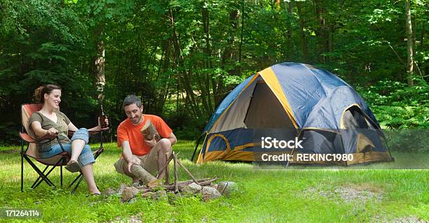 Uomo E Donna In Campeggio Tenda A Un Fuoco Di Accampamento - Fotografie stock e altre immagini di Amicizia