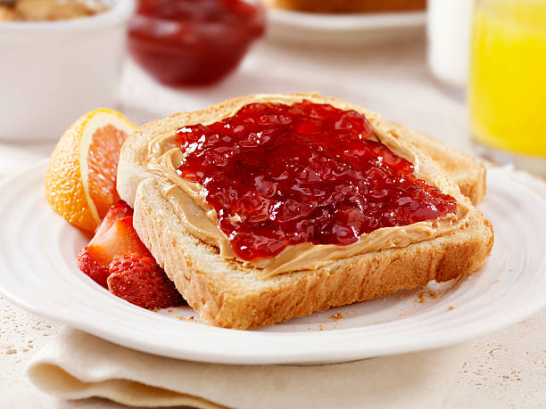 Peanut Butter and Jam on Toast Peanut Butter and Strawberry Jam on Toast with Orange Juice and Milk- Photographed on Hasselblad H3D2-39mb Camera peanut butter and jelly sandwich stock pictures, royalty-free photos & images