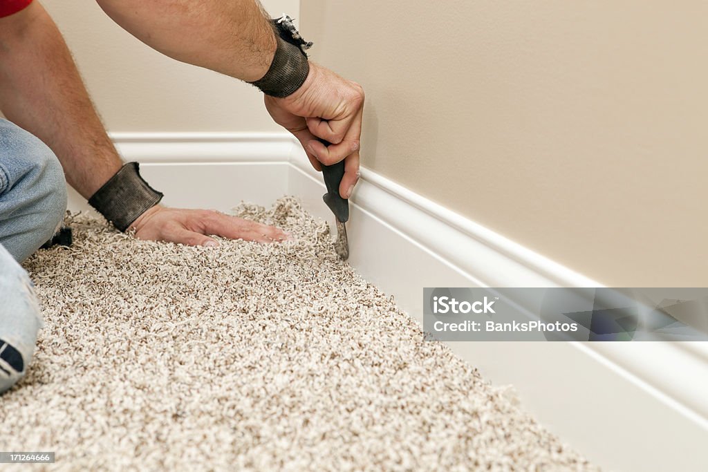 Instalador utilizando cuchilla para ordenar alfombra nueva piso - Foto de stock de Moqueta libre de derechos