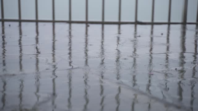 Raindrops ripple on street, static handheld