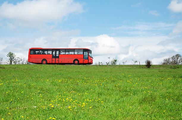 istock Red bus driving on country road through spring meadow 171264893
