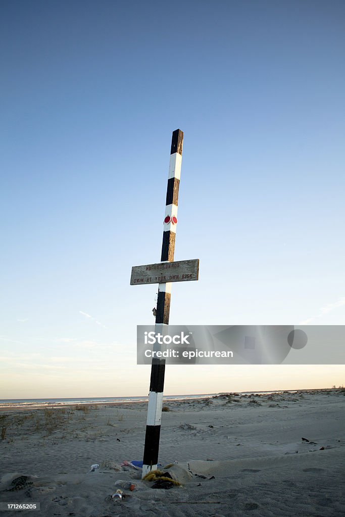 Pole and sign in sand on cumberland island beach Pole stuck in sand on beach with various debris and trash around base. Beach Stock Photo