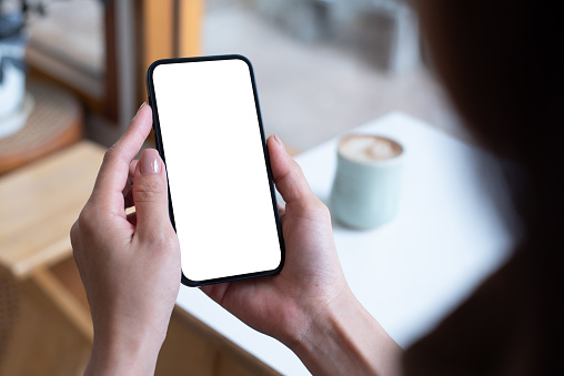 Mockup, woman's hand holding using mobile phone at coffee shop with copy space, white blank screen for text, mobile app design and advertsing, online marketing