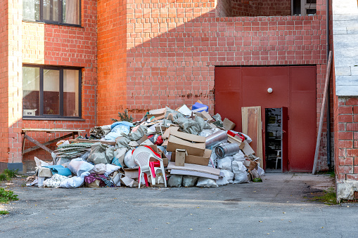 A large pile of construction debris is located near a brick building