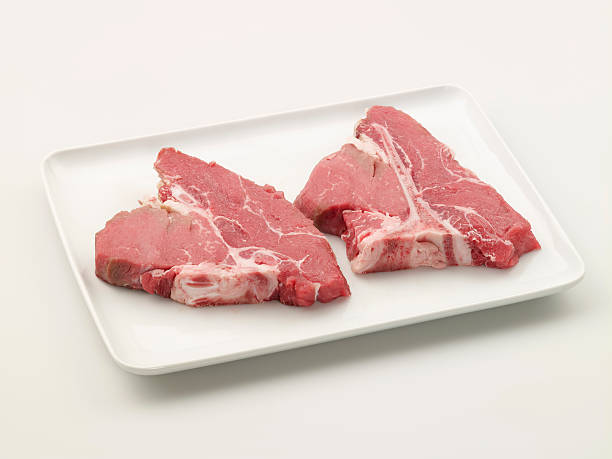 необработанные стейк на косточке на тарелке - meat raw beef love стоковые фото и изображения