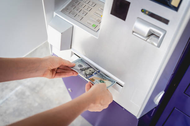 Young woman holding money in her hands after withdrawing the cash at the ATM Young woman holding money in her hands after withdrawing the cash at the ATM. exchange teller stock pictures, royalty-free photos & images