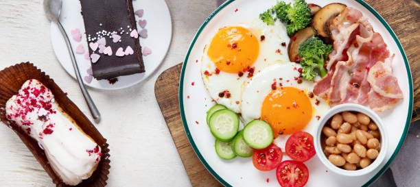 tradycyjny talerz śniadaniowy englis z paskami bekonu, słonecznymi jajkami, warzywami i ciastem na jasnym tle - englis zdjęcia i obrazy z banku zdjęć