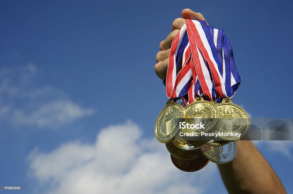 Atleta Mão segurando o monte de medalhas de ouro céu azul - Foto de stock de Evento multiesportivo internacional royalty-free