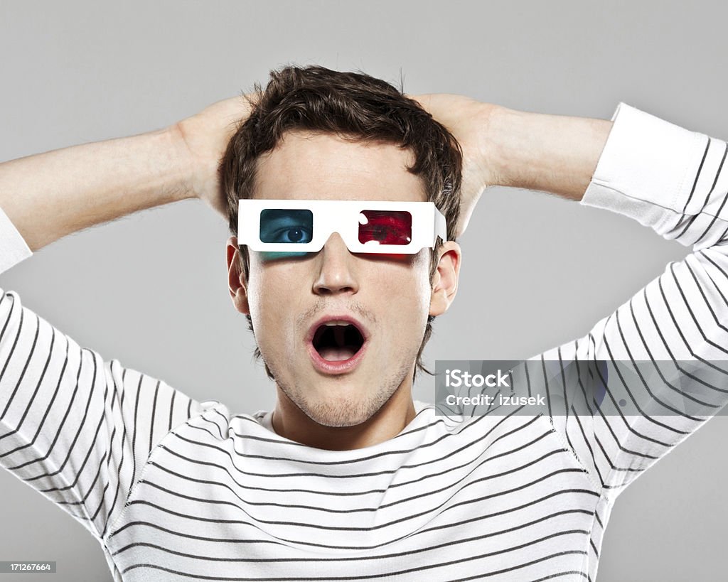 Shocked man wearing 3D glasses Portrait of shocked young man wearing 3D glasses. Studio shot, grey background. 3-D Glasses Stock Photo