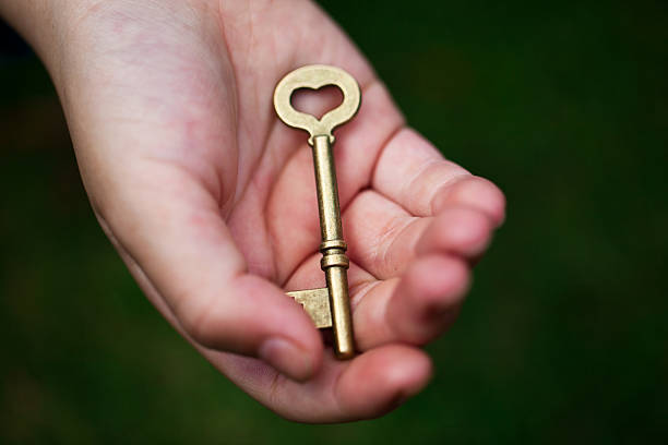 main tenant la clé de la réussite - human hand key giving carrying photos et images de collection