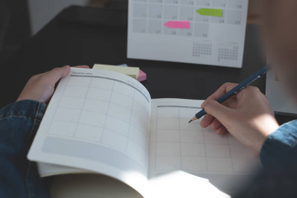 istock Event planner timetable agenda plan on year 2024 schedule event. Business woman checking timetable, taking note on calendar planner notebook on office table. Calendar event plan, work planning, mockup 1712680437