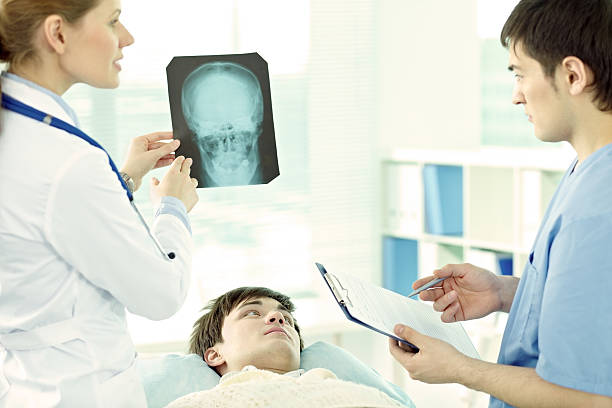 Head injury Young man lying in hospital with head injury, doctor examining his brain x-ray concussion stock pictures, royalty-free photos & images