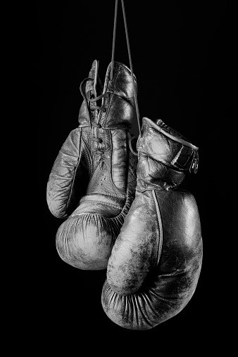Vintage beaten,decayed black white boxing gloves on black background