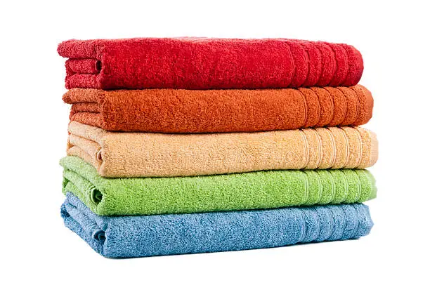 Five stacked bath towels isolated on white background. Blue, green, red, yellow and orange. Front and side view, studio shot.
