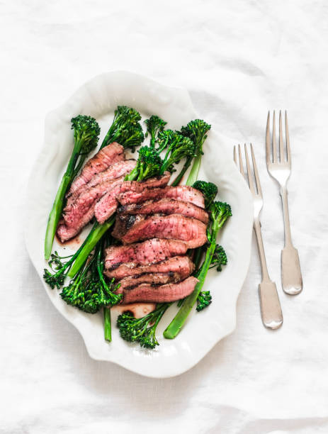 Grilled beef steak and broccolini - delicious lunch, appetizer, tapas on a light background, top view