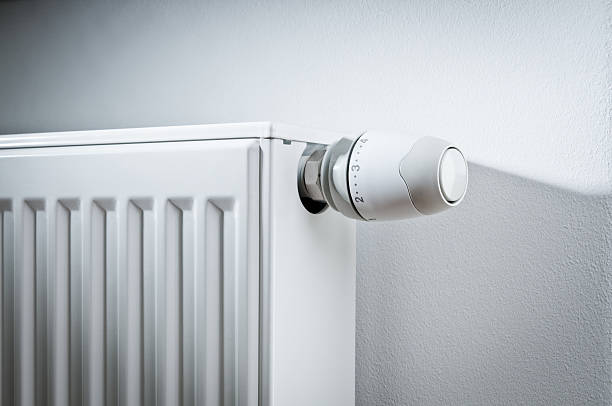 Modern white radiator with thermostat reduced to economy mode Close-up of modern white radiator with thermostat reduced to economy mode. radiator heater photos stock pictures, royalty-free photos & images