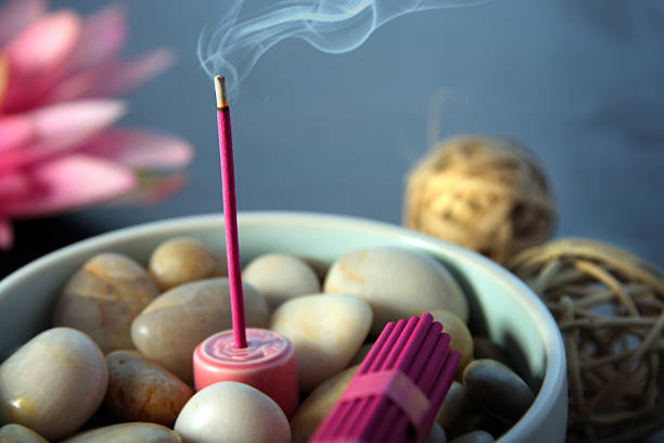 Burning Incense Pink incense stick smouldering in a bowl of river pebbles.  Themes of relaxation, aromatherapy and eastern rituals. incense photos stock pictures, royalty-free photos & images