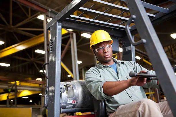 Photo of African American worker driving forklift