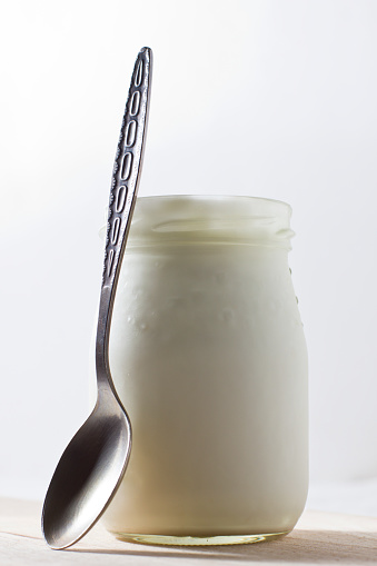 white yogurt in glass jar with spoon 