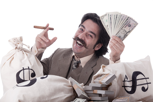 Rich man posing with money bags and dollar bills.He has handle bar mustaches and smoking cigar.The model is wearing a suit and necktie.The background is white.Shot with a full frame DSLR camera in studio with a horizontal framing.