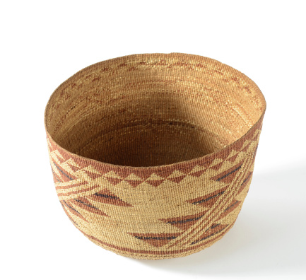 Antique Native American woven basket set on a white background.
