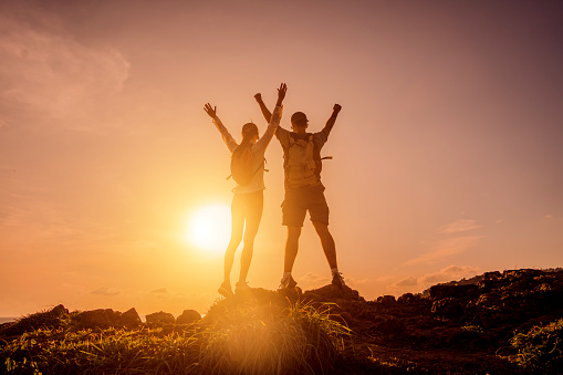 Happy young couple climbs to the top in the mountains near the ocean.