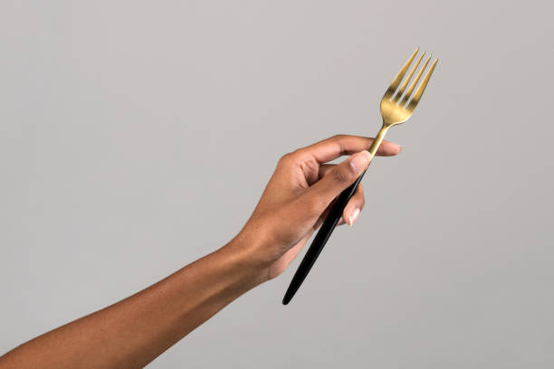 istock Crop woman hand holding fork in gray studio 1712717812