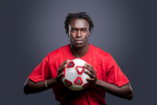 Soccer player model holding a ball and looking at the camera